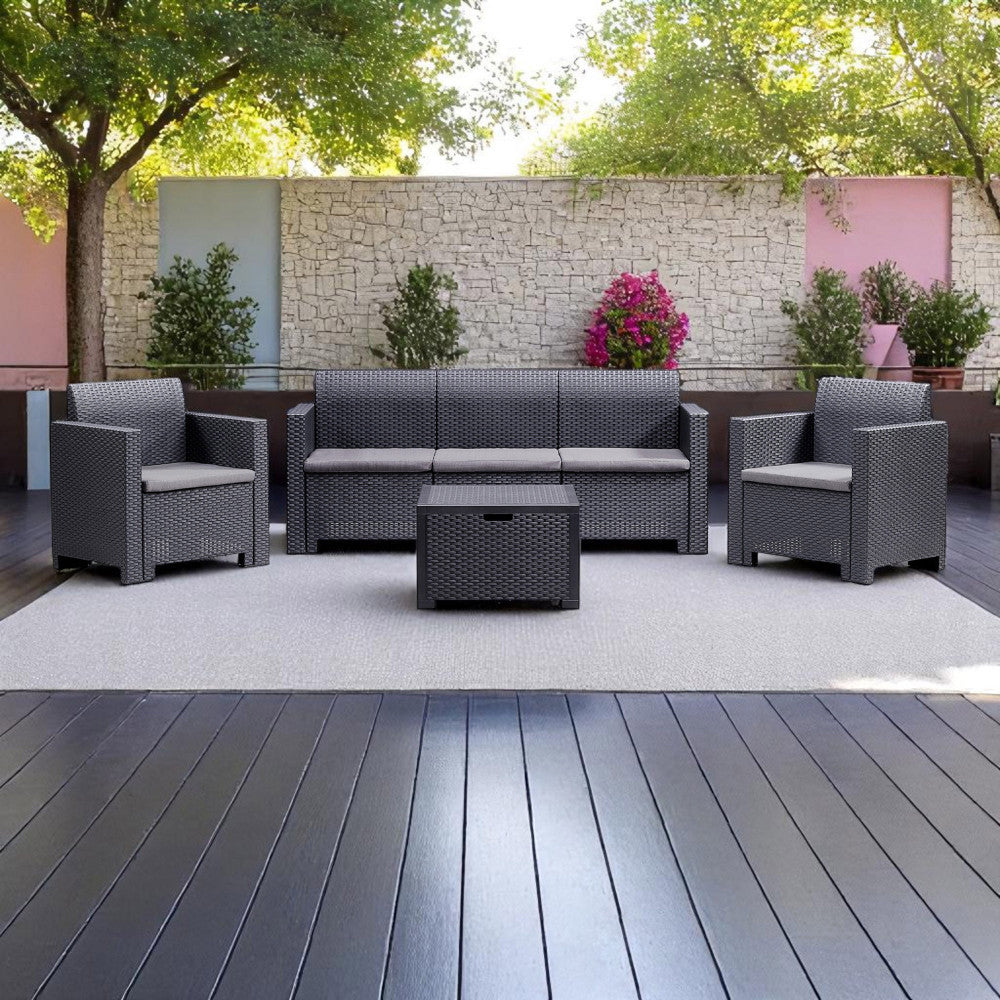 Set da esterno Nebraska posizionato su un elegante deck in legno scuro con tappeto chiaro e muro in pietra sullo sfondo.