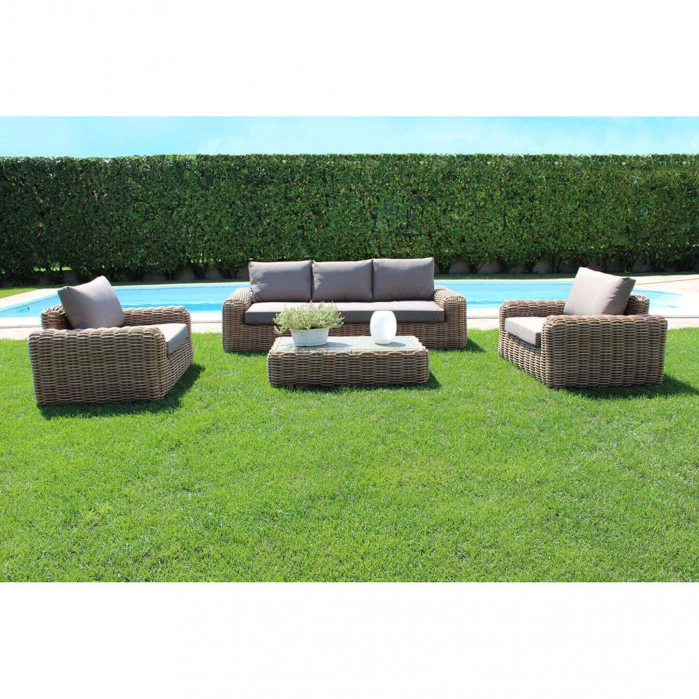 Il salotto Ramirez posizionato su un prato curato a bordo piscina, che illustra la perfetta integrazione del wicker marrone nell'ambiente outdoor.
