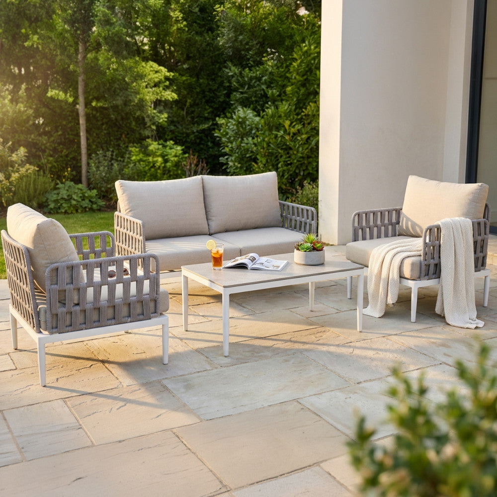 Vista frontale del salotto moderno a quattro posti, integrato in un elegante patio esterno con pavimentazione in pietra.