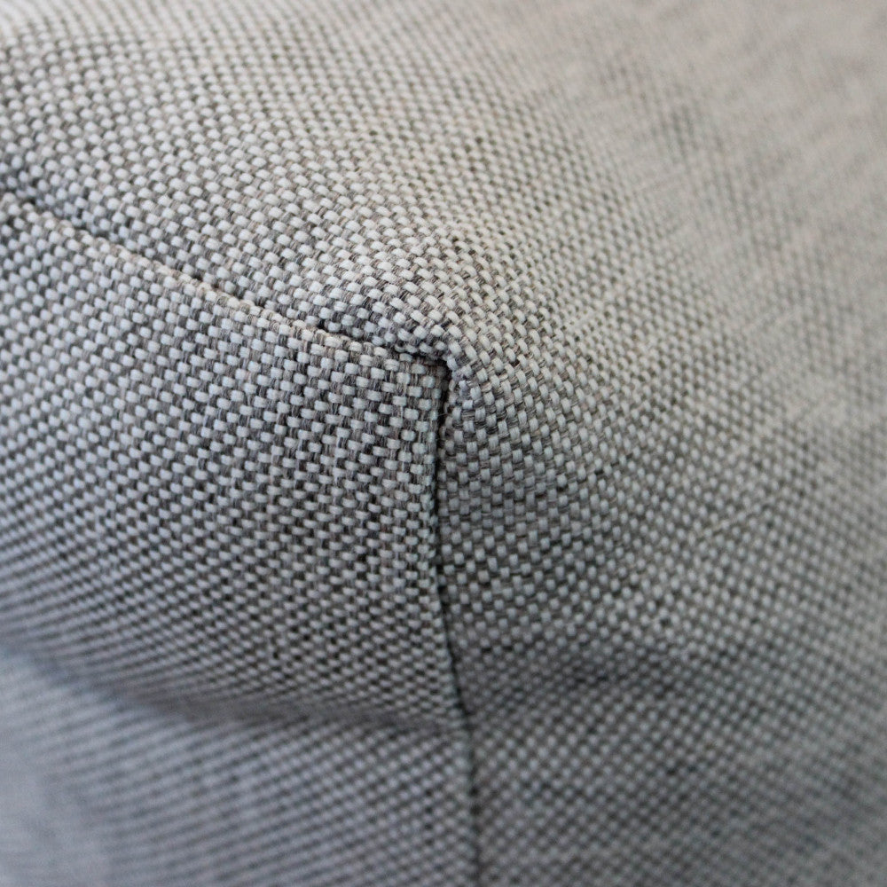 Primo piano della texture del tessuto in poliestere grigio chiaro del cuscino, che ne evidenzia la trama fitta e resistente.