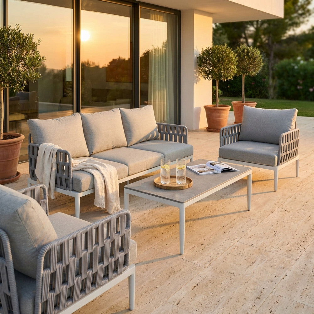 Dettaglio del salotto moderno con divano e poltrone su una terrazza in travertino al tramonto.