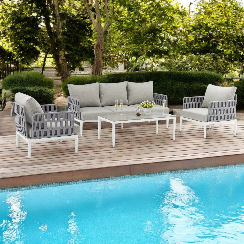 Salotto outdoor in corda intrecciata posizionato su un deck in legno a bordo piscina.