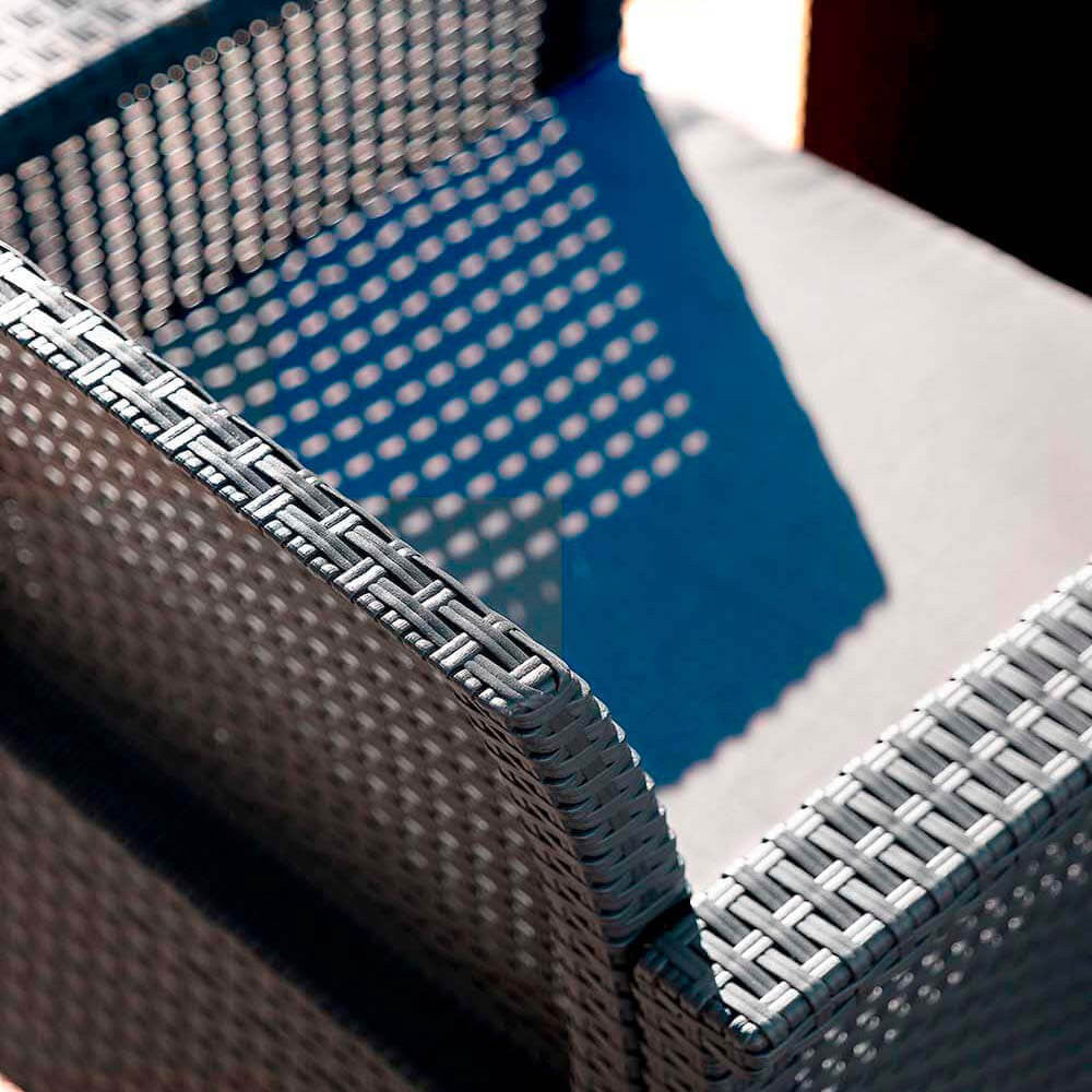Primo piano della texture intrecciata del bracciolo in polipropilene nero con cuscino grigio sfoderabile.