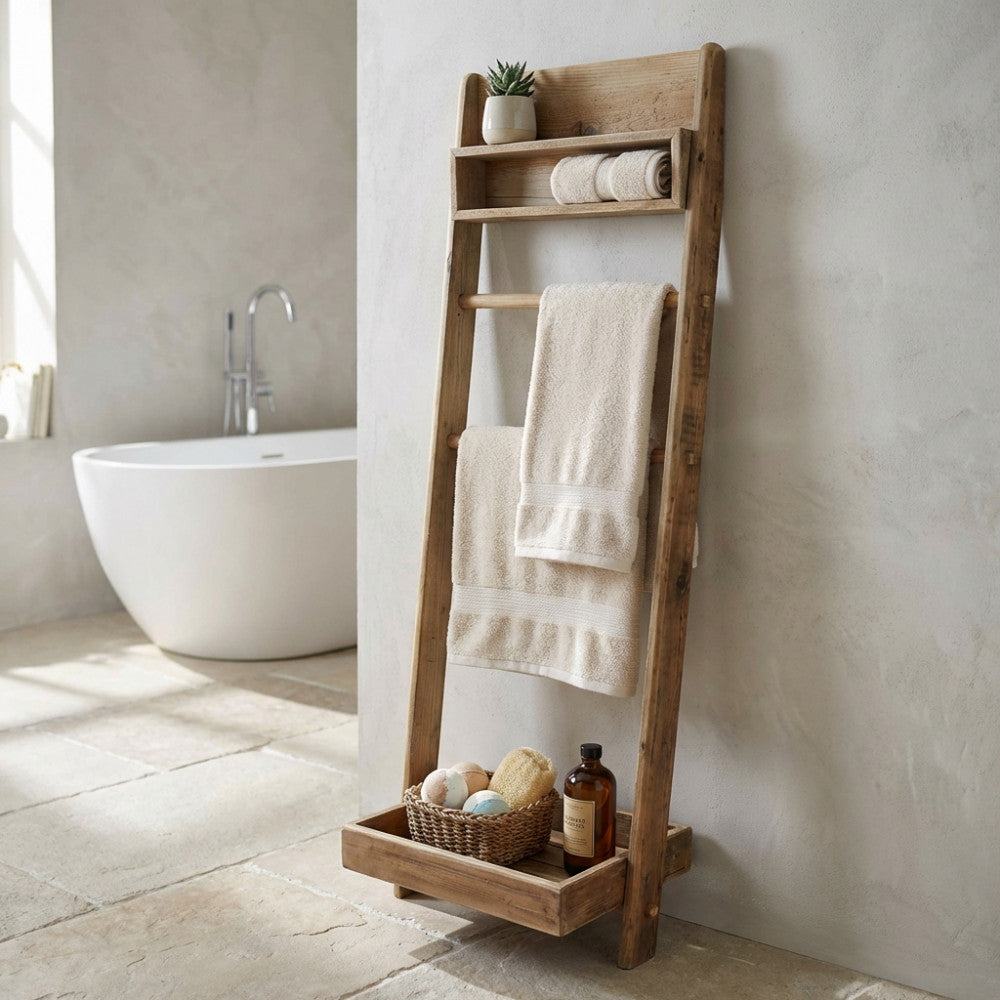 Scaffale da bagno a scala Biddy in pino riciclato marrone, allestito con asciugamani e accessori accanto a una vasca bianca.