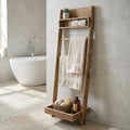 Scaffale da bagno a scala Biddy in pino riciclato marrone, allestito con asciugamani e accessori accanto a una vasca bianca.