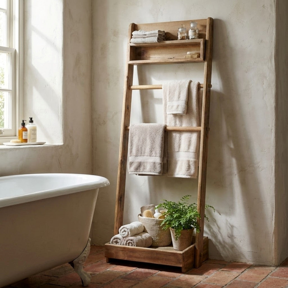 Scaffale Biddy ambientato in un bagno rustico-chic con pavimento in cotto, decorato con piante e tessili in spugna.