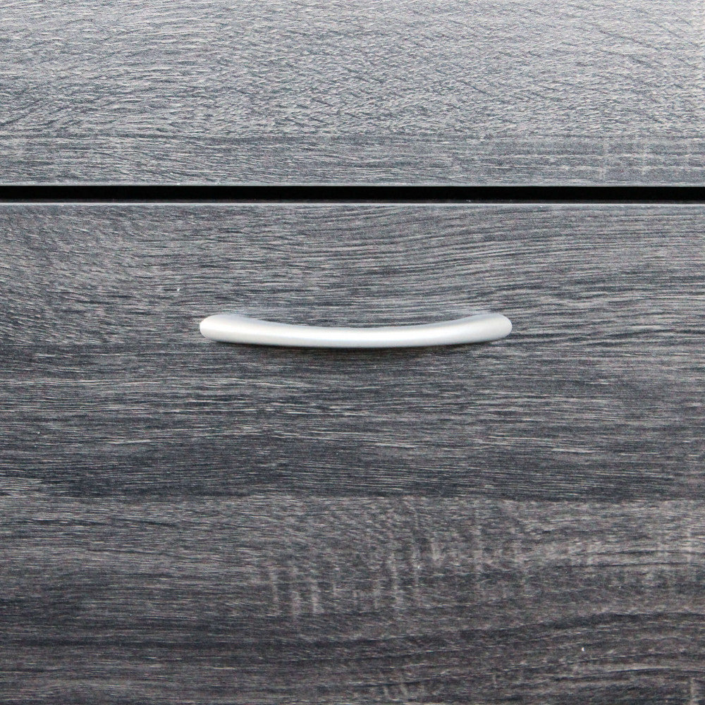 Primo piano della maniglia curva in metallo satinato applicata sul pannello in legno grigio scuro.
