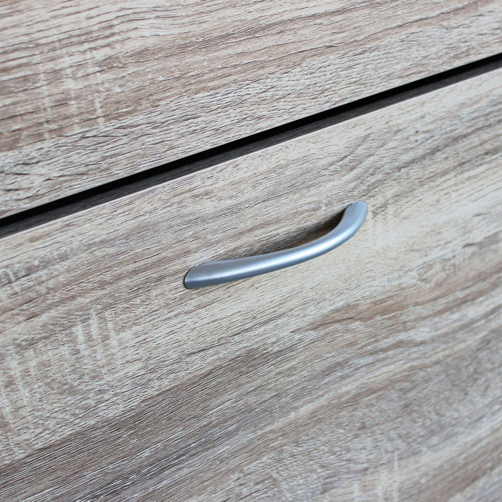 Dettaglio della maniglia curva in metallo satinato applicata sul frontale in legno marrone.