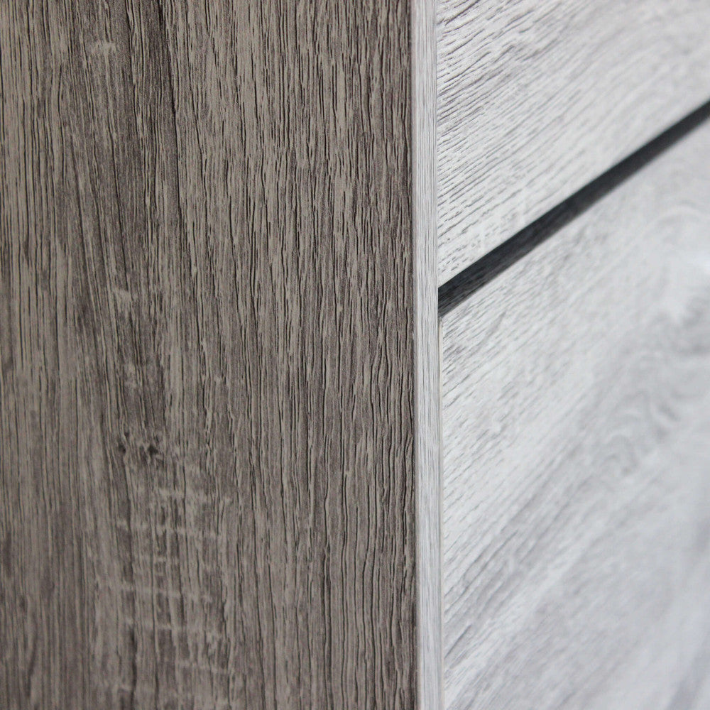 Dettaglio ravvicinato dello spigolo della scarpiera, che mostra la texture tattile delle venature del legno grigio chiaro.