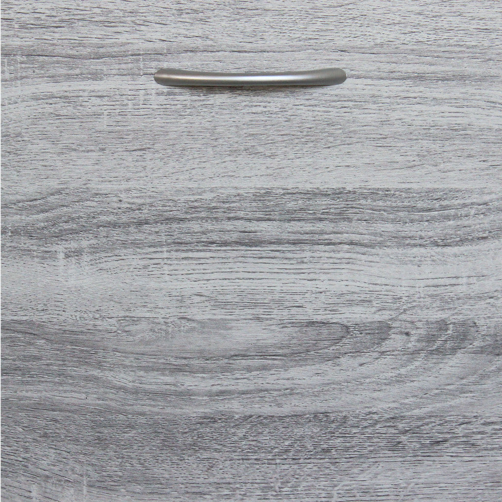Primo piano del pannello frontale in legno grigio chiaro con maniglia minimalista in metallo satinato.