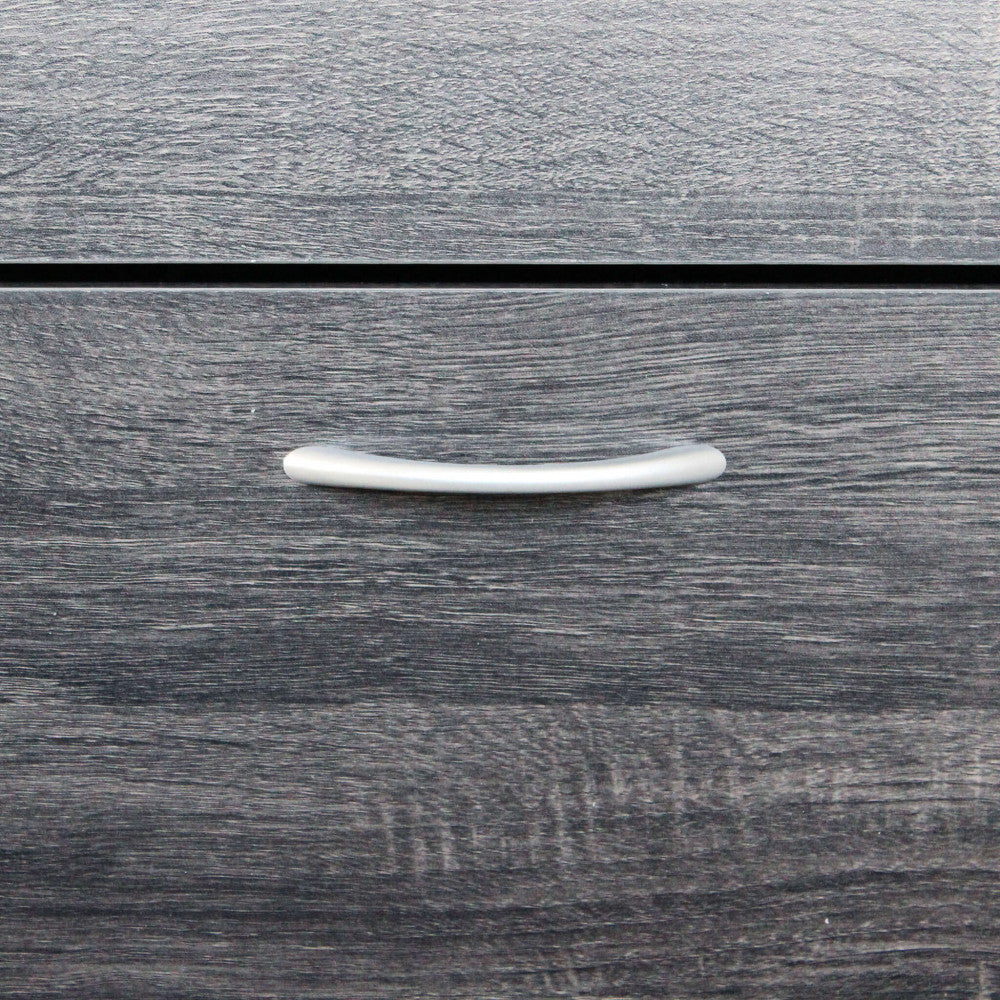 Dettaglio ravvicinato della maniglia curva in metallo satinato sul pannello in legno grigio scuro.