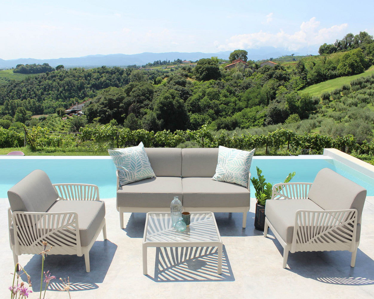Set lounge Guaranà completo di tavolino, divano e poltrone in un lussuoso patio estivo.