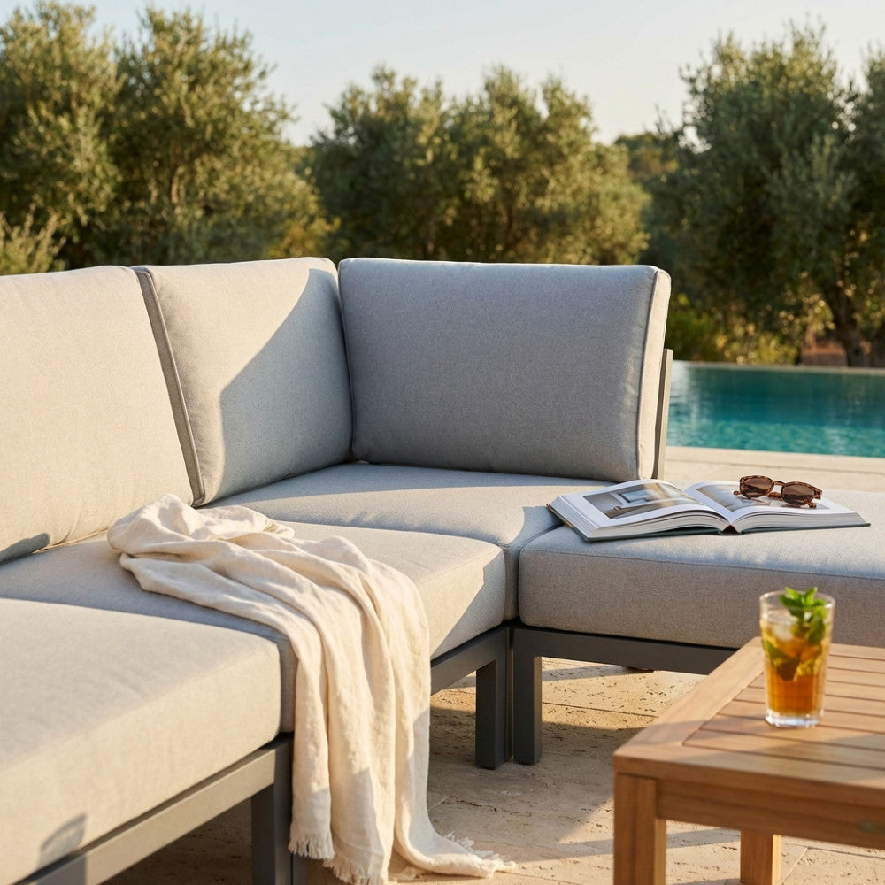 Salotto da esterni con schienale angolare, cuscini morbidi e accessori relax.