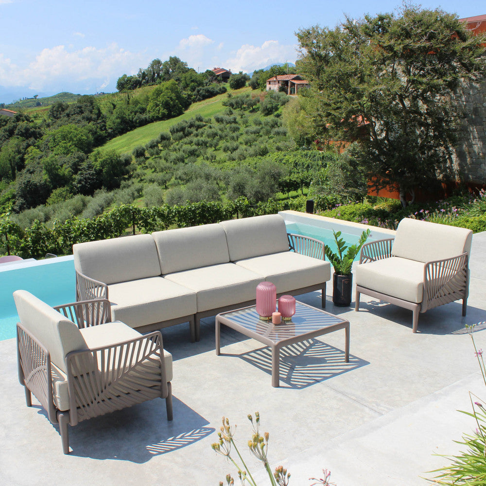 Set lounge da esterno Guaranà con schienali intrecciati, posizionato su una terrazza soleggiata.
