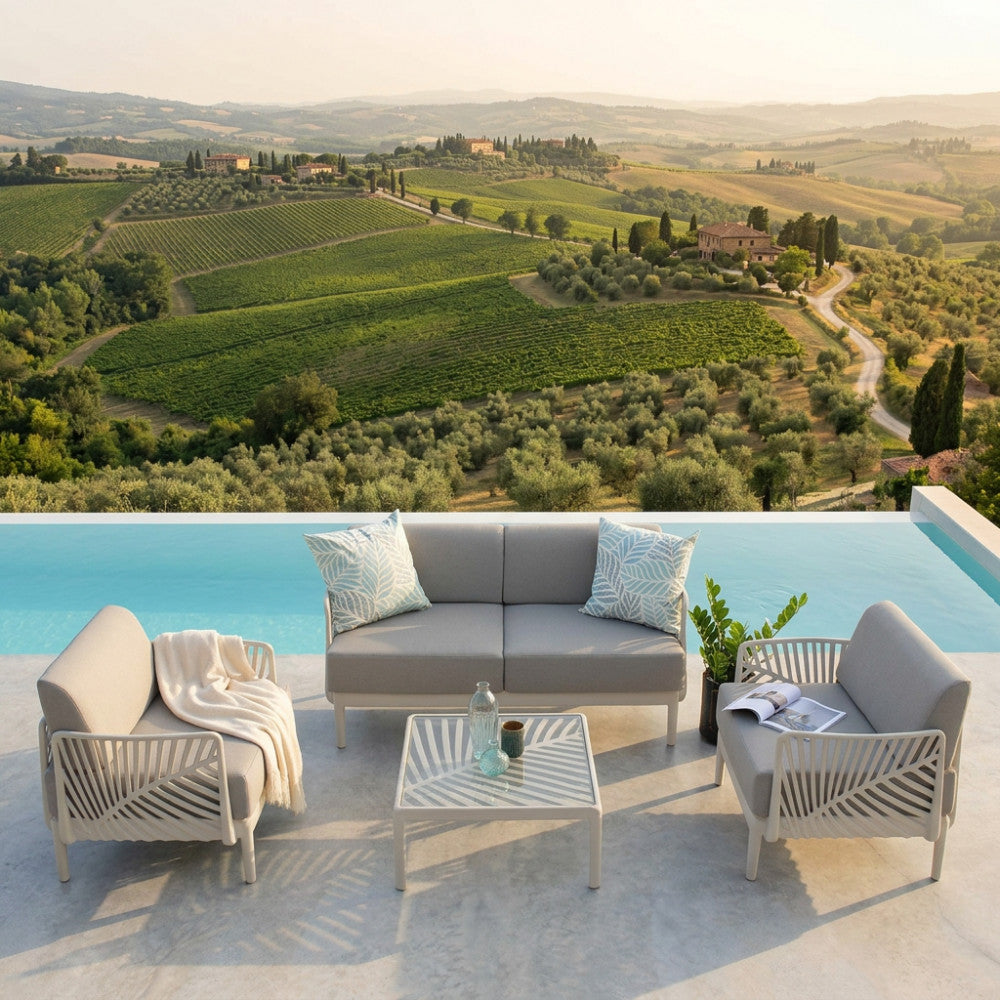 Set lounge Guaranà in polipropilene tortora illuminato dalla calda luce del tramonto in un giardino di lusso.