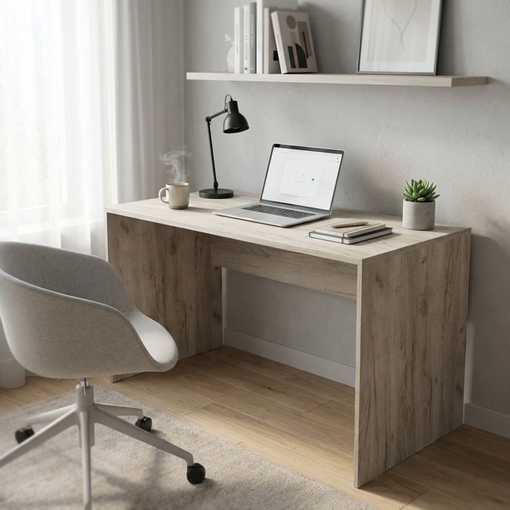 Vista angolare della scrivania Josie in truciolare bilaminato rovere grigio, abbinata a una sedia ergonomica in tessuto chiaro.