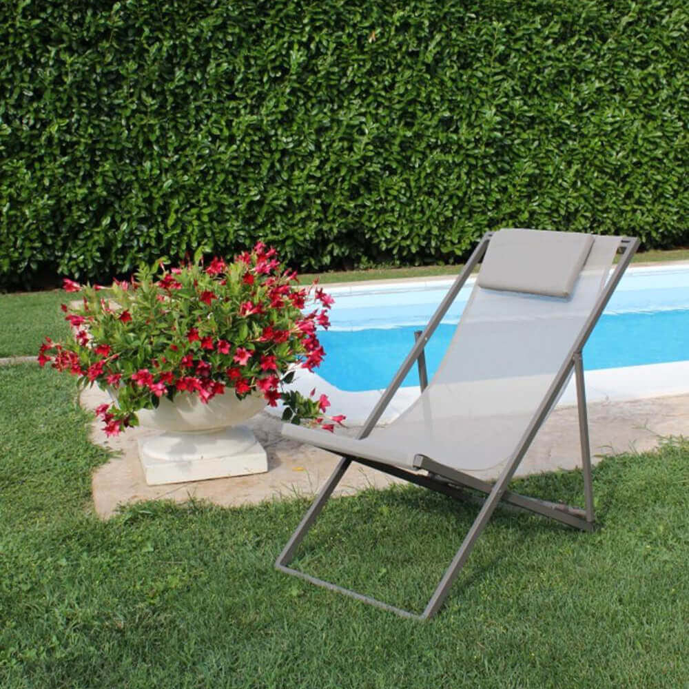 Sdraio Avana color tortora posizionata su un prato curato vicino a una piscina e a una fioriera decorativa.