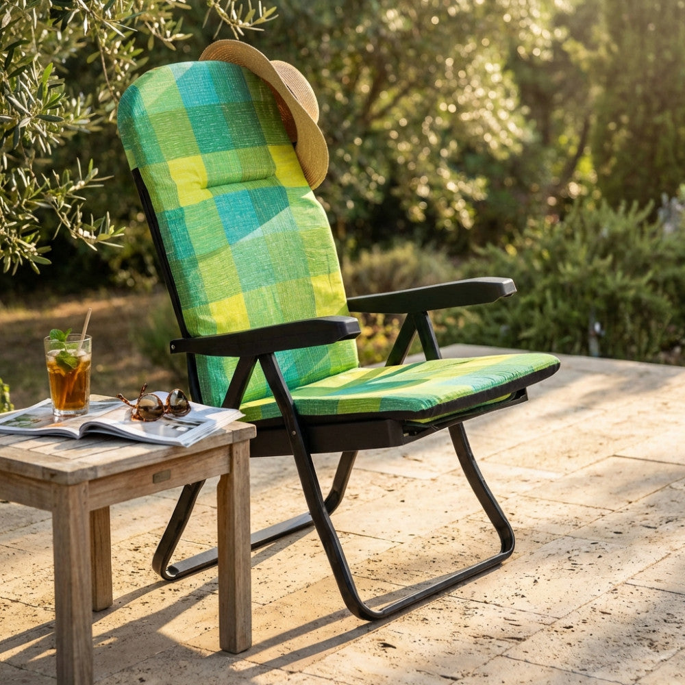 Poltrona relax Cipro con motivo tartan in un patio soleggiato, affiancata da un tavolino in legno con bibita estiva.