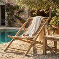 Sdraio Dondolo Bellini in legno marrone a bordo piscina con telo chiaro.