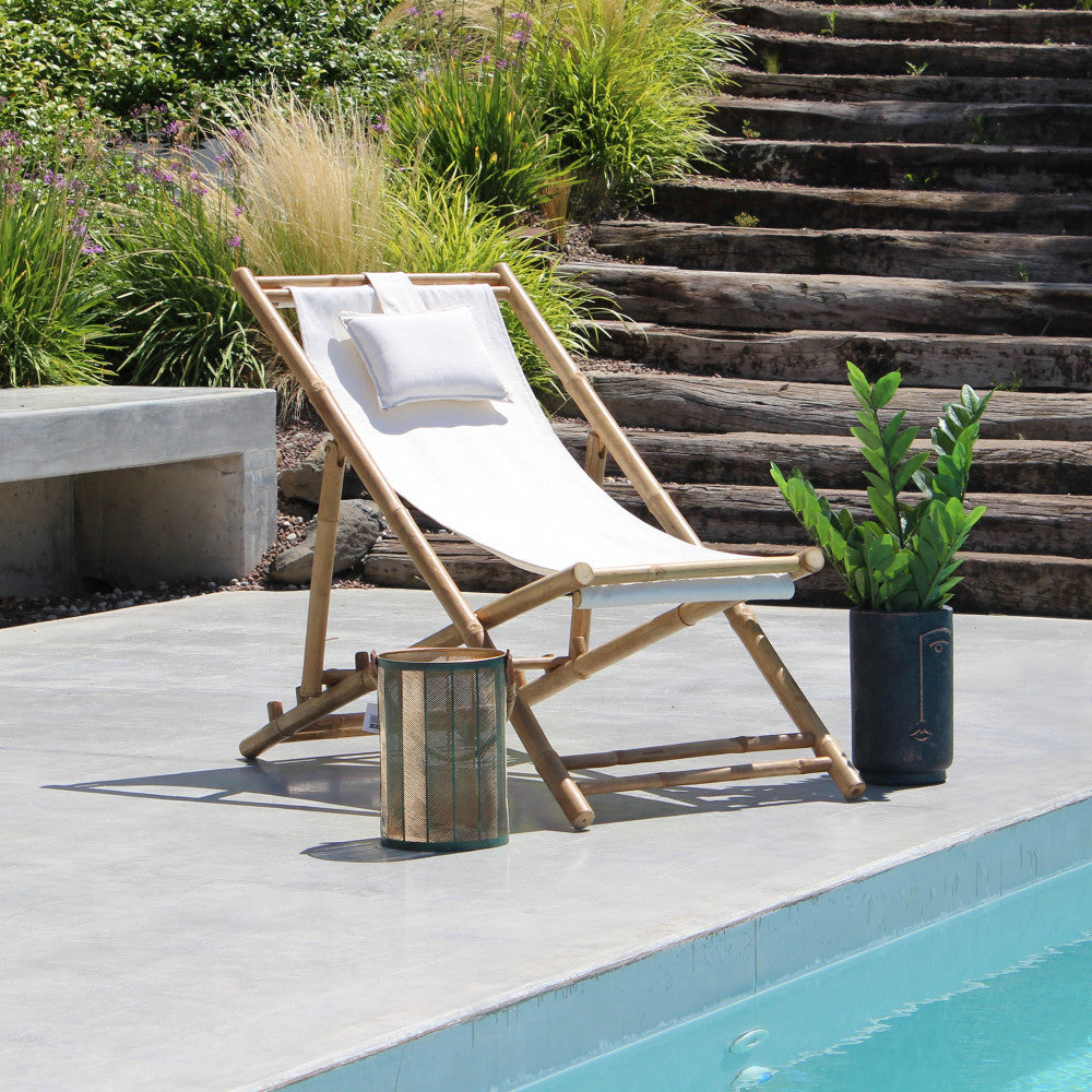Sdraio Daiquiri in legno inserita in un contesto di design a bordo piscina, affiancata da una lanterna decorativa e vegetazione lussureggiante.