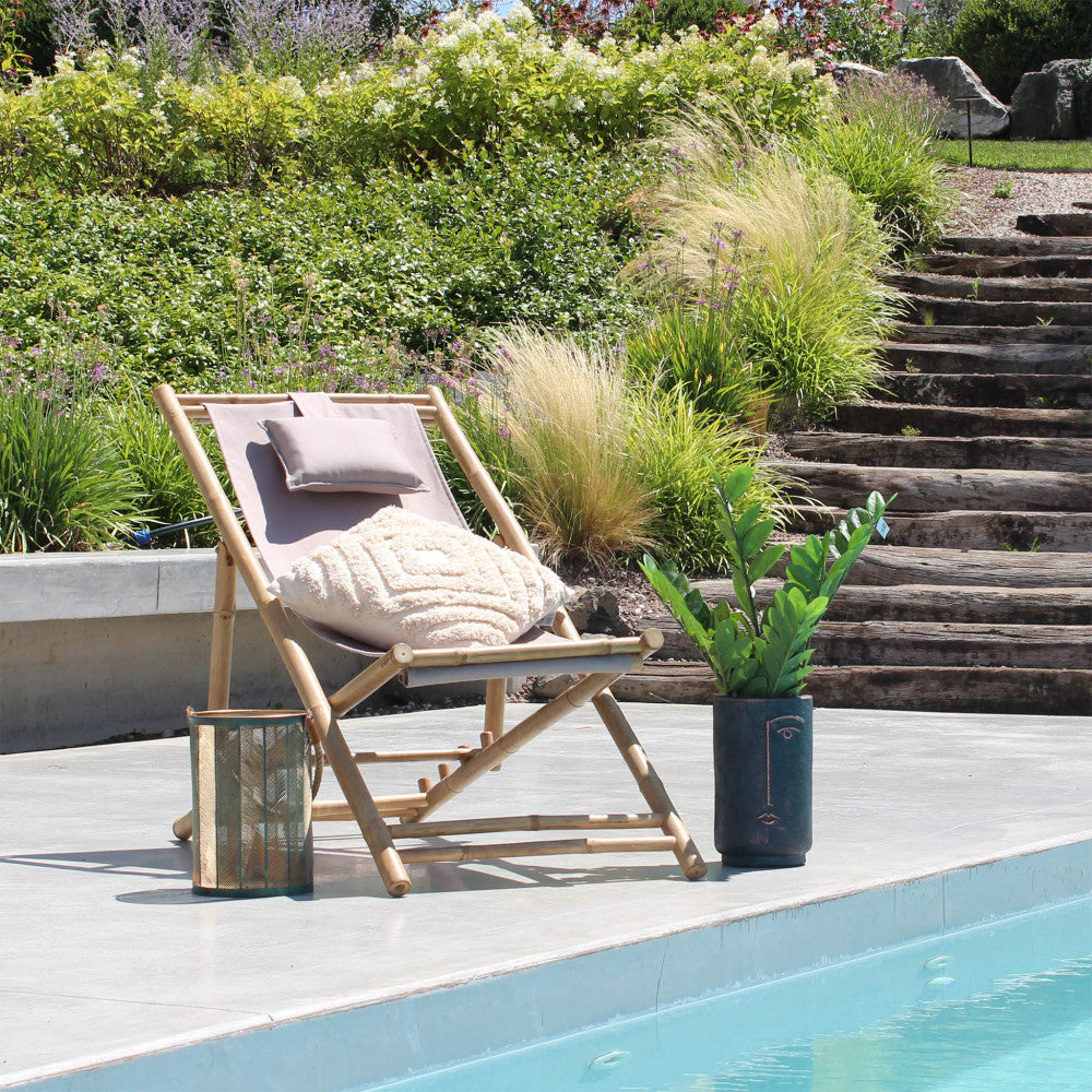 Sdraio Daiquiri ambientata a bordo piscina con cuscino decorativo e vaso scuro con pianta verde.