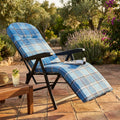 Poltrona relax Rodi in tessuto scozzese blu posizionata su un patio in cotto, illuminata dalla luce naturale del tramonto.