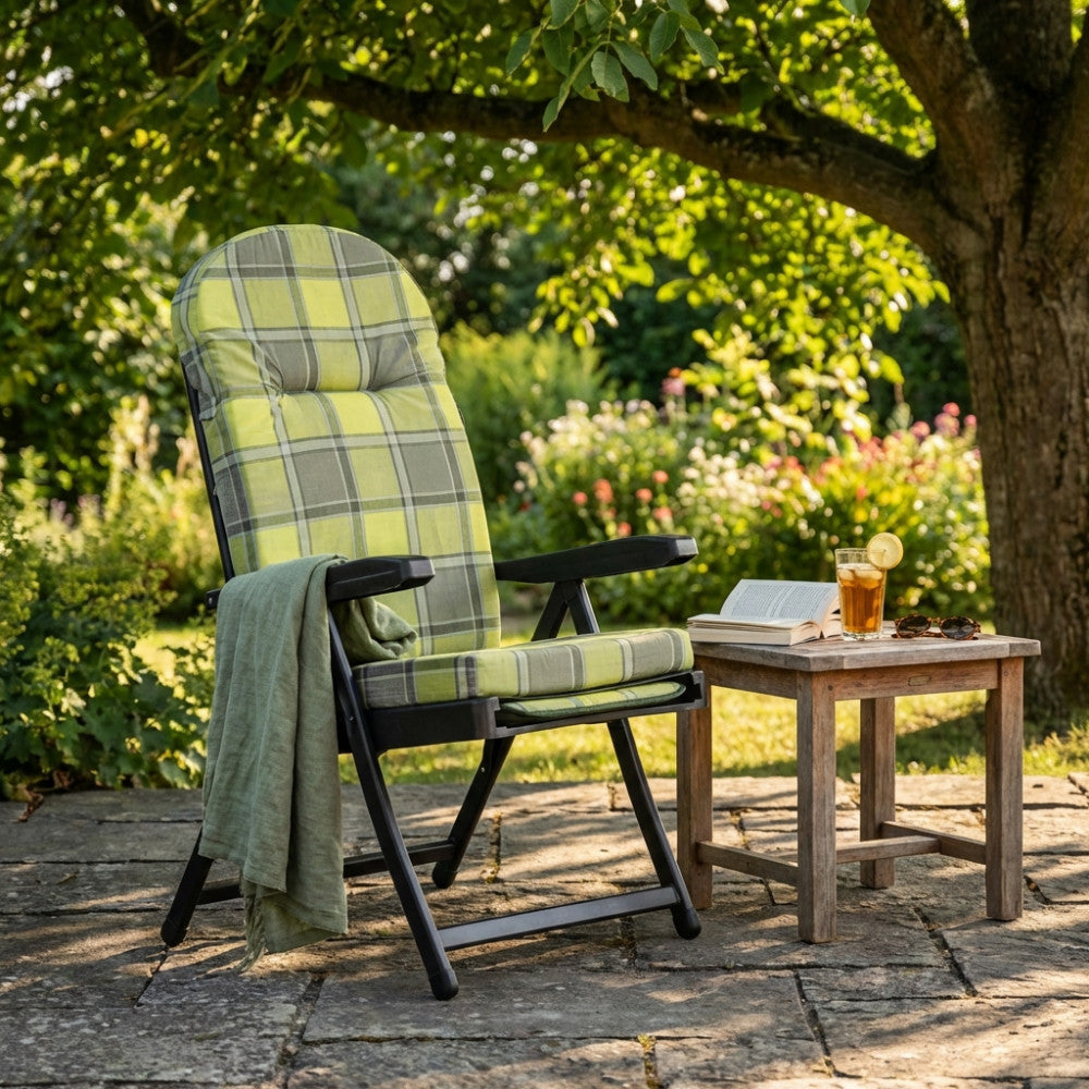 Sdraio relax in acciaio e tessuto ambientata in un rigoglioso giardino sotto l'ombra di un albero.
