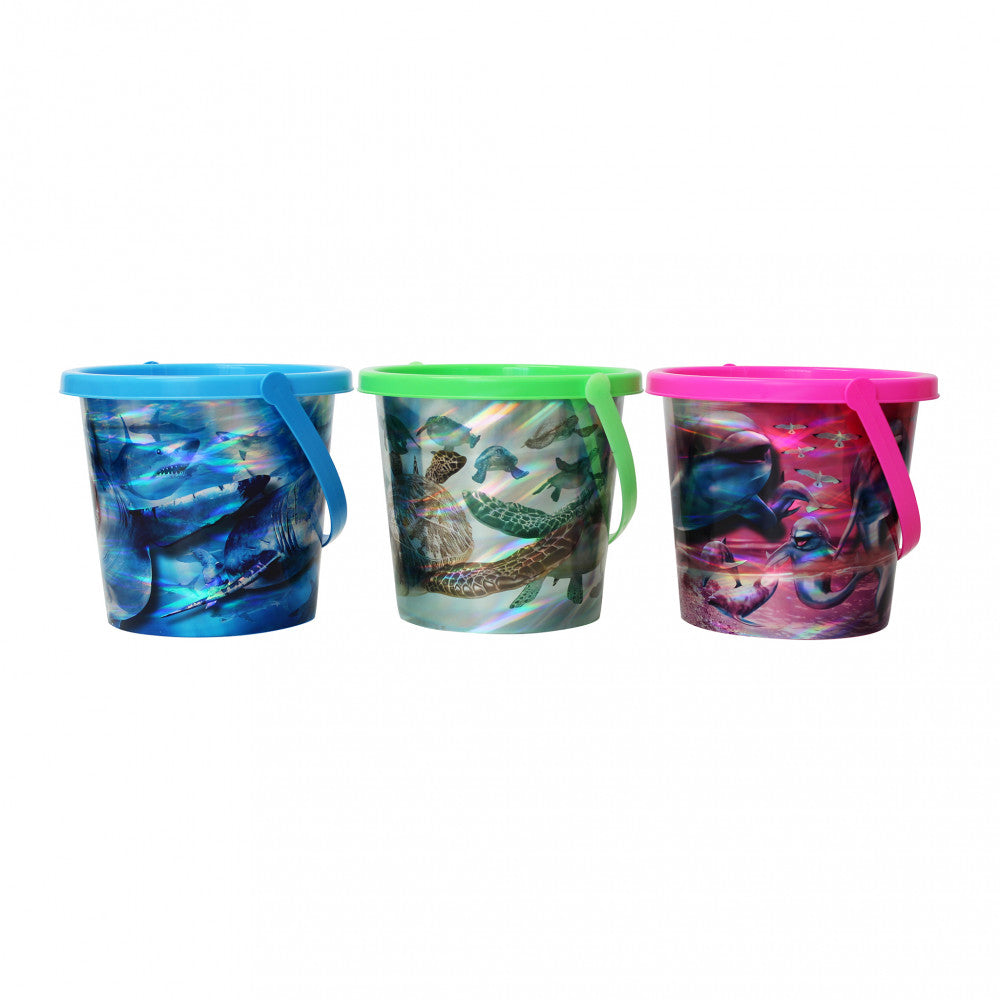 Tre secchielli per giochi mare con grafiche di animali marini, in colori blu, verde e rosa, disposti in fila su sfondo bianco.