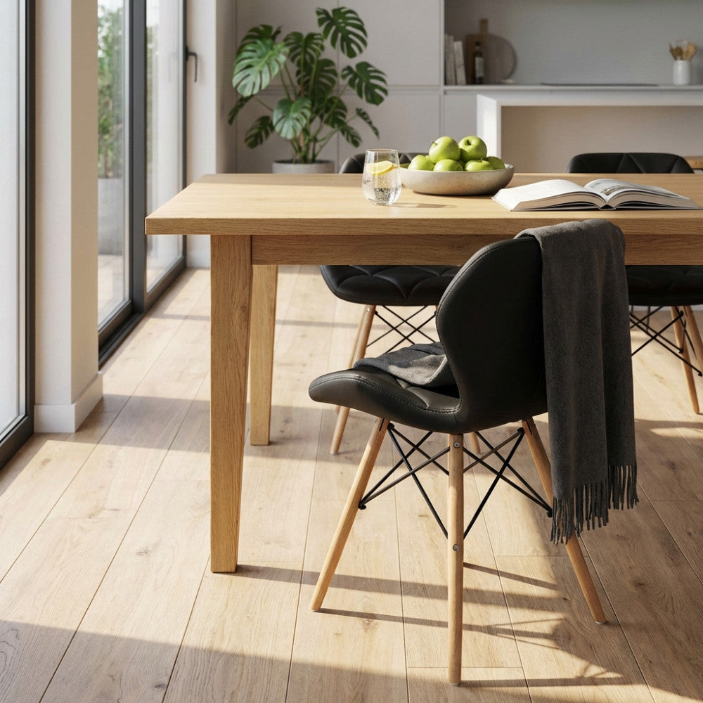 Sedia Annapolis nera posizionata accanto a un tavolo da pranzo in legno chiaro in un ambiente luminoso.