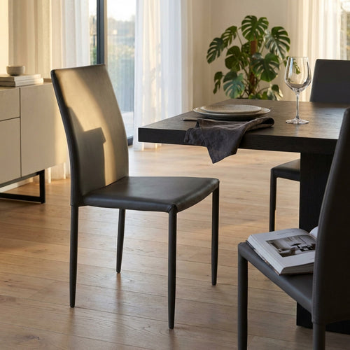 Sedia Cammie in ecopelle marrone posizionata in una luminosa sala da pranzo moderna.