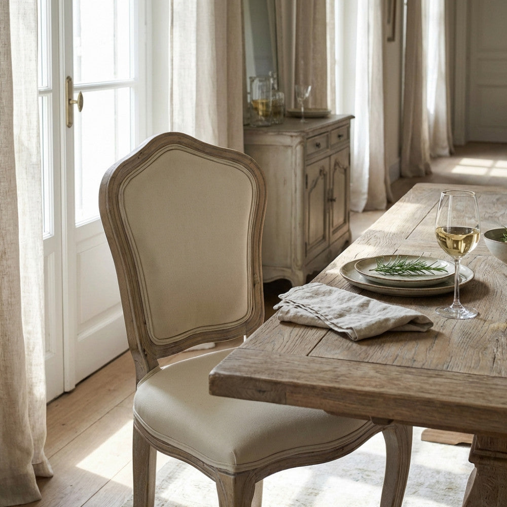 Dettaglio dello schienale sagomato della sedia Charlene accanto a una tavola apparecchiata con calici di vino.