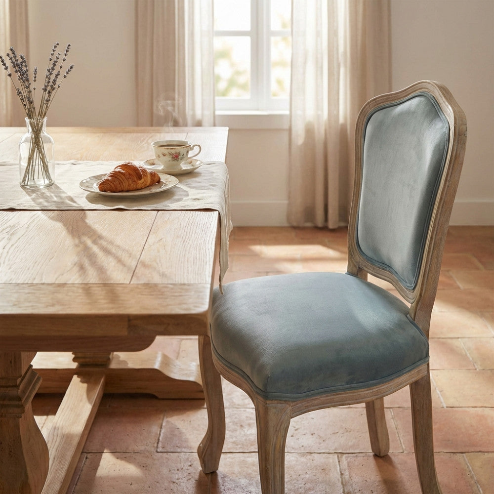 Sedia da pranzo Charlene in velluto grigio in un ambiente luminoso con colazione su tavolo in legno.