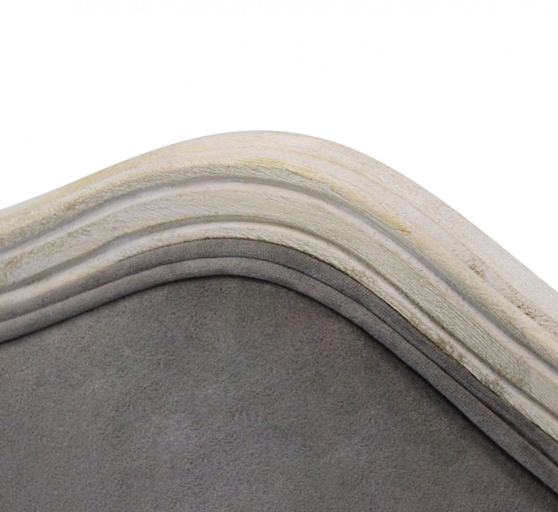 Dettaglio ravvicinato della cornice in legno intagliato e del rivestimento in velluto taupe.