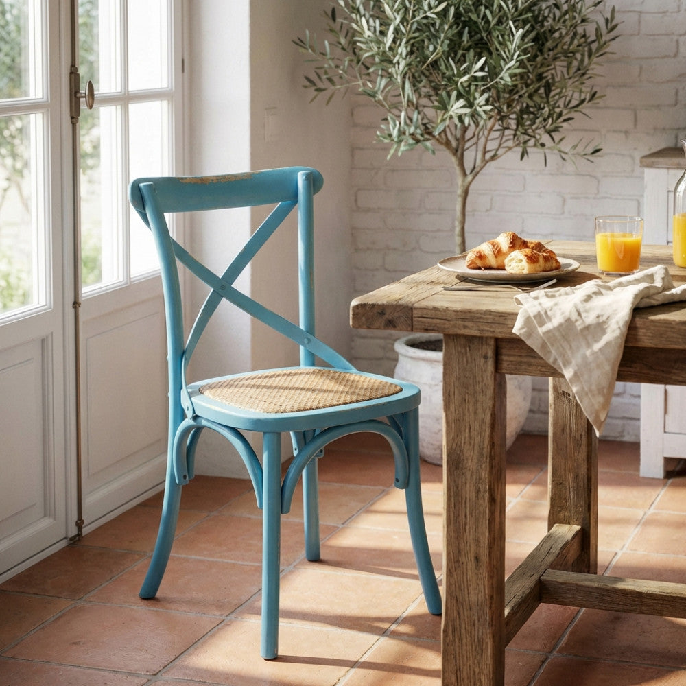 Sedia da interno Cross Azzurra in legno inserita in una luminosa zona pranzo con un ulivo.