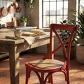 Sedia rustica Cross rossa in legno e rattan ambientata in una cucina luminosa con tavolo in legno.