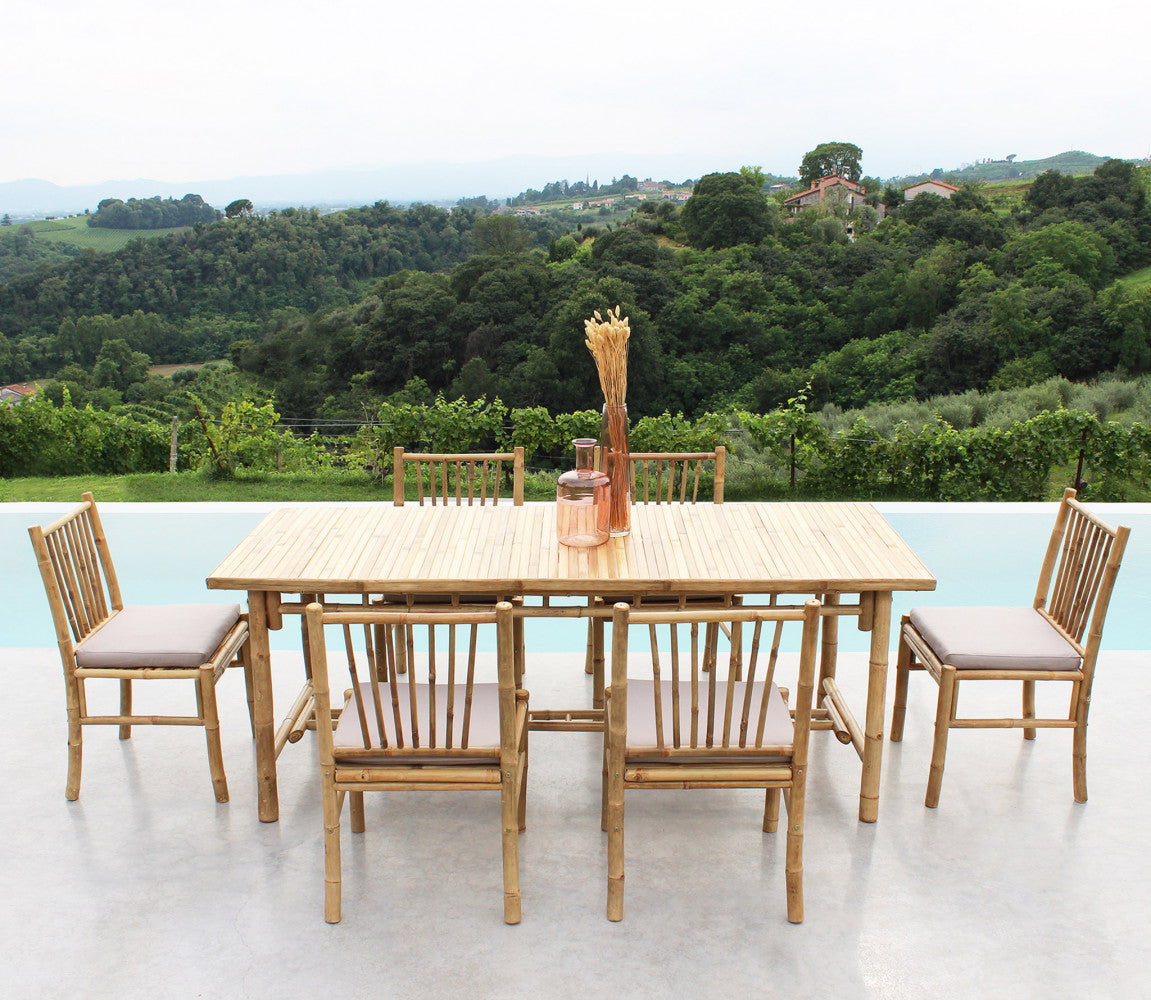 Set da pranzo all'aperto con sei sedie in legno e tavolo abbinato con vista su colline verdi.