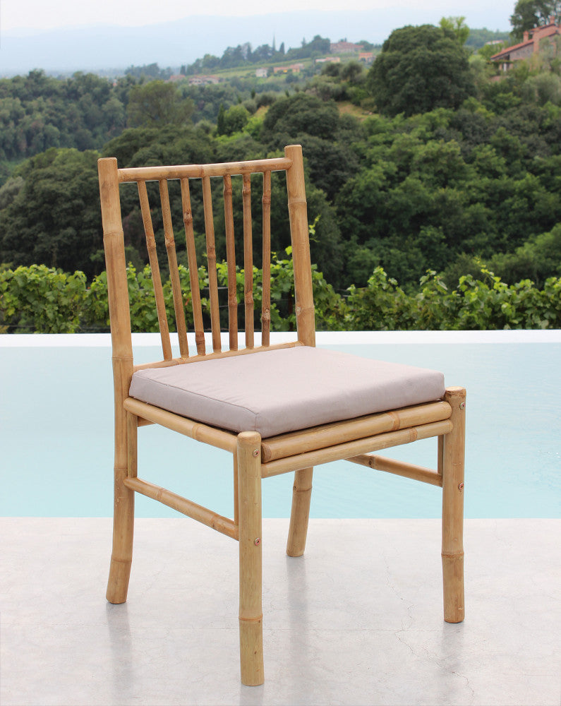 Sedia in legno posizionata a bordo piscina con panorama collinare lussureggiante sullo sfondo.