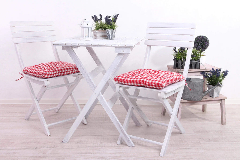 Sedia Dalila Bianca ripieghevole in Legno di Acacia massiccio, design senza braccioli per esterni, ambientata con tavolino e cuscini