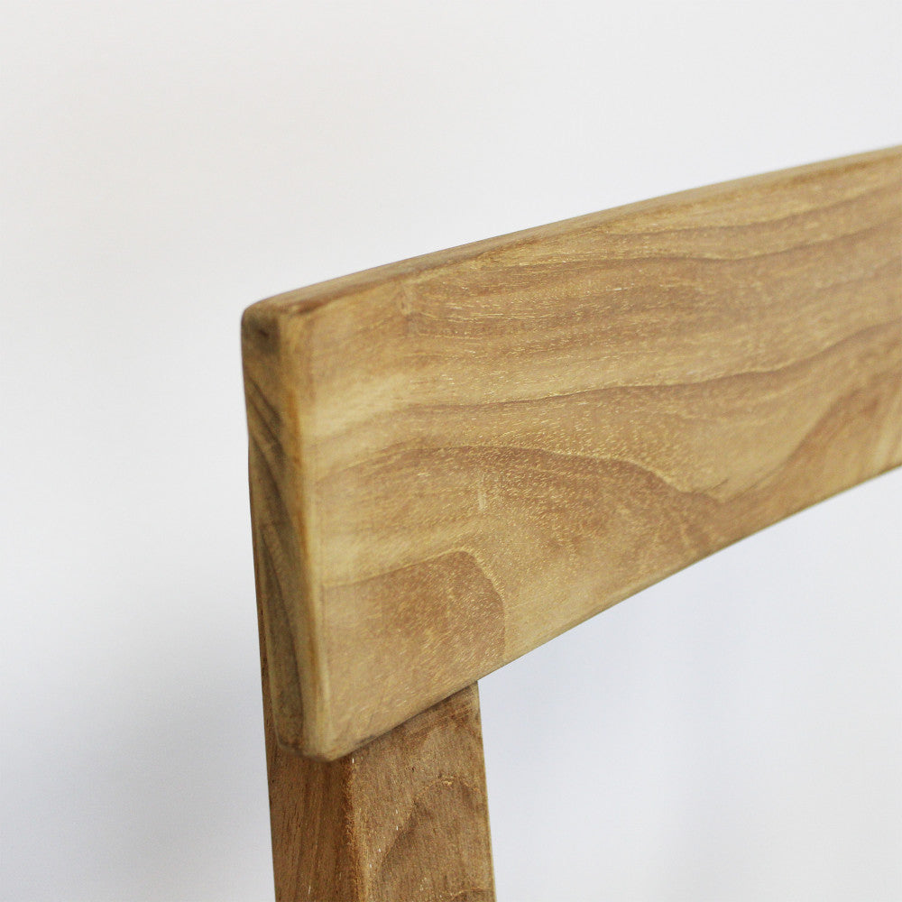 Dettaglio ravvicinato dello schienale curvo in teak, che rivela le venature calde e organiche del materiale.