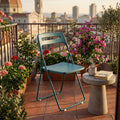Sedia ELISABETH in acciaio verde petrolio ambientata su un balcone cittadino al tramonto.