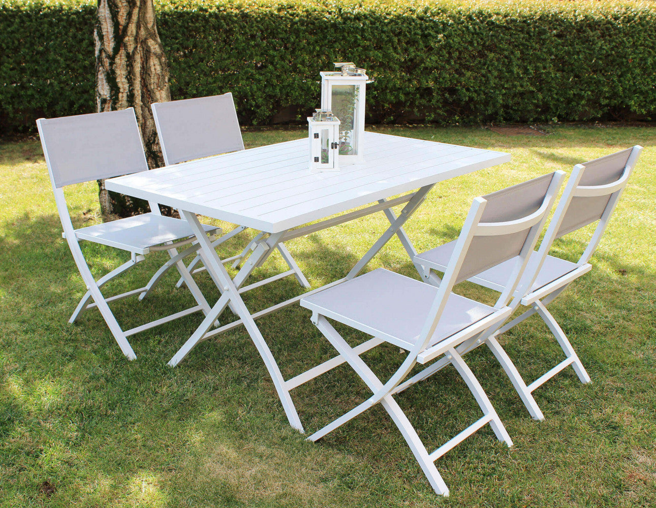 Set da pranzo outdoor con quattro sedie Georgia e tavolo bianco su un prato verde curato.