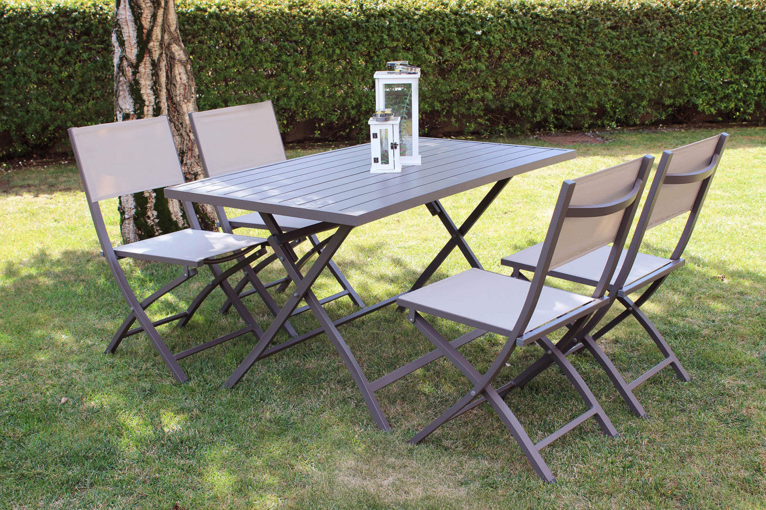 Composizione outdoor con tavolo rettangolare e quattro sedie Georgia color taupe su un prato curato.