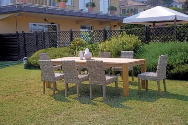 Sedia Lisbona Grey Kubu con struttura in legno e seduta in fibra naturale, ideale per interni e verande, ambientata n giardino con tavolo rettangolare