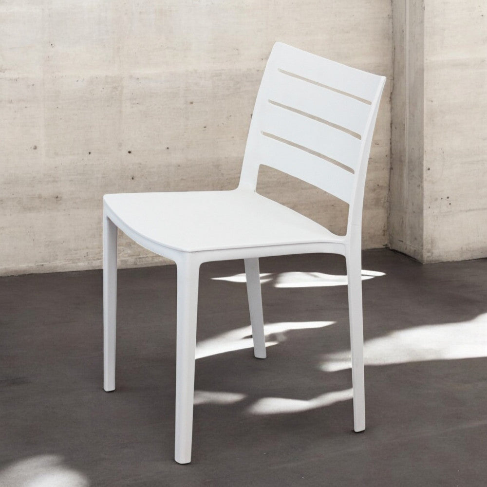 Sedia Hallie bianca in polimero illuminata dalla luce naturale in un ambiente minimalista.
