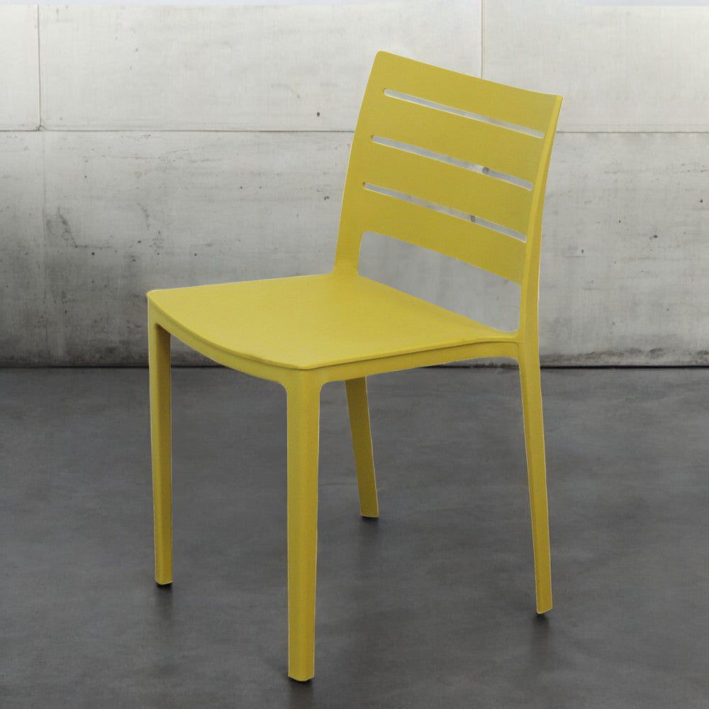 Sedia in polimero tecnico giallo Hallie, vista frontale angolata su pavimento scuro e parete in cemento.