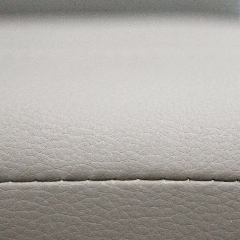 Dettaglio ravvicinato della texture in ecopelle tortora con cuciture sartoriali a vista.