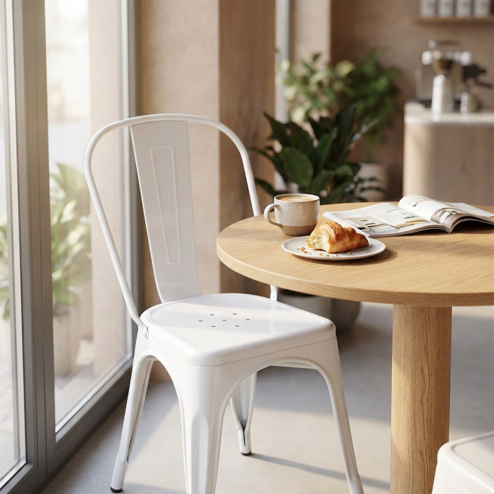 Sedia Lola bianca in stile industrial posizionata accanto a un tavolo rotondo in legno chiaro con colazione.