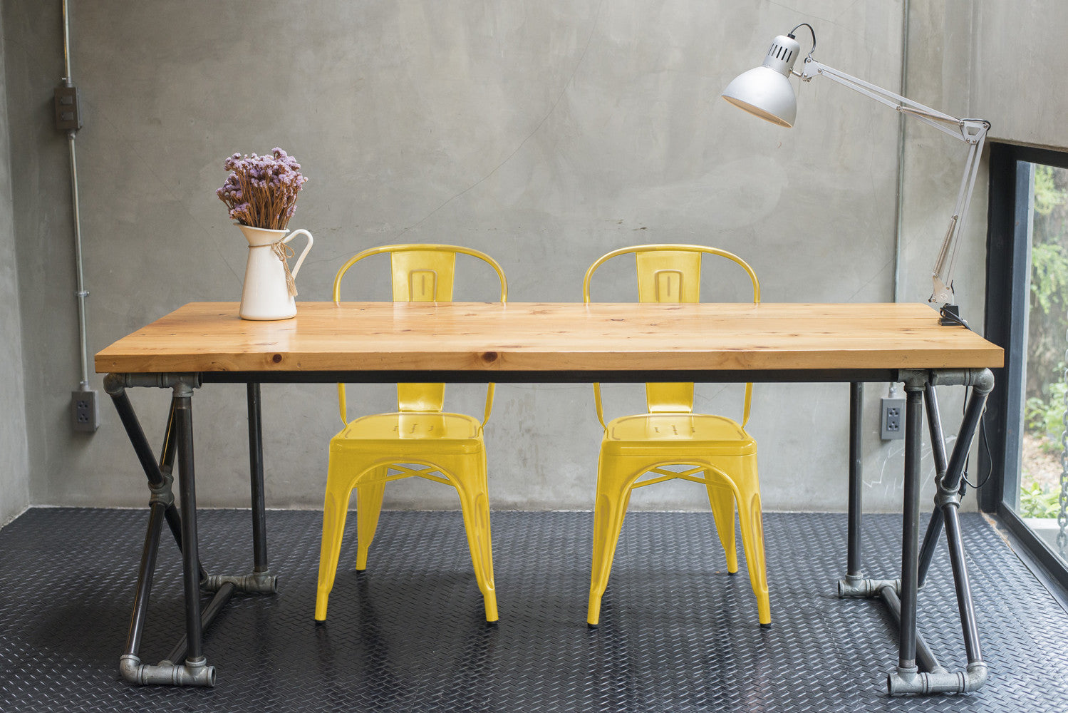 Due sedie in acciaio giallo antico sotto una lampada da tavolo in un contesto dal design metropolitano.
