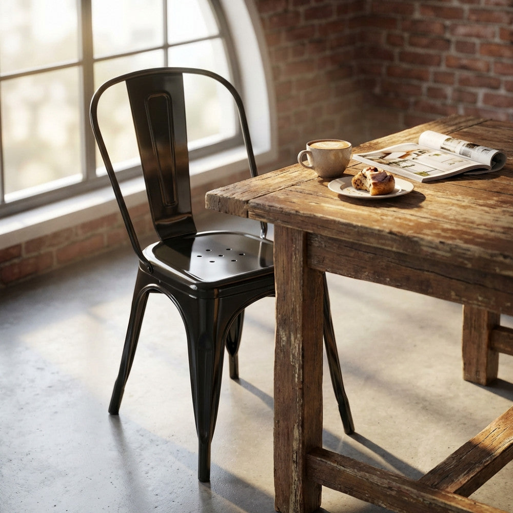 Sedia Lola nera in metallo accostata a un tavolo da pranzo rustico in legno con colazione.