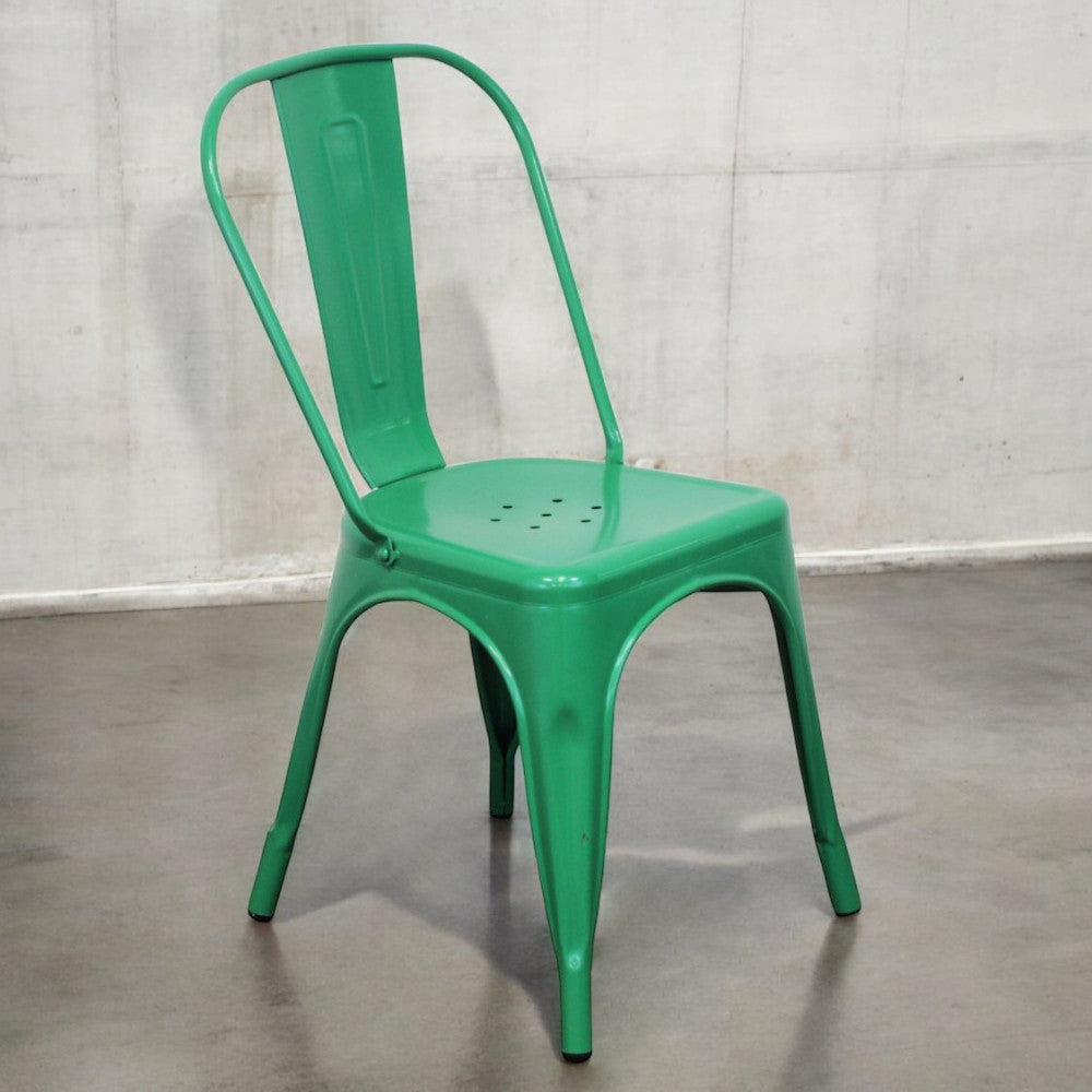 Sedia Lola verde fotografata di tre quarti su un pavimento in cemento industriale.